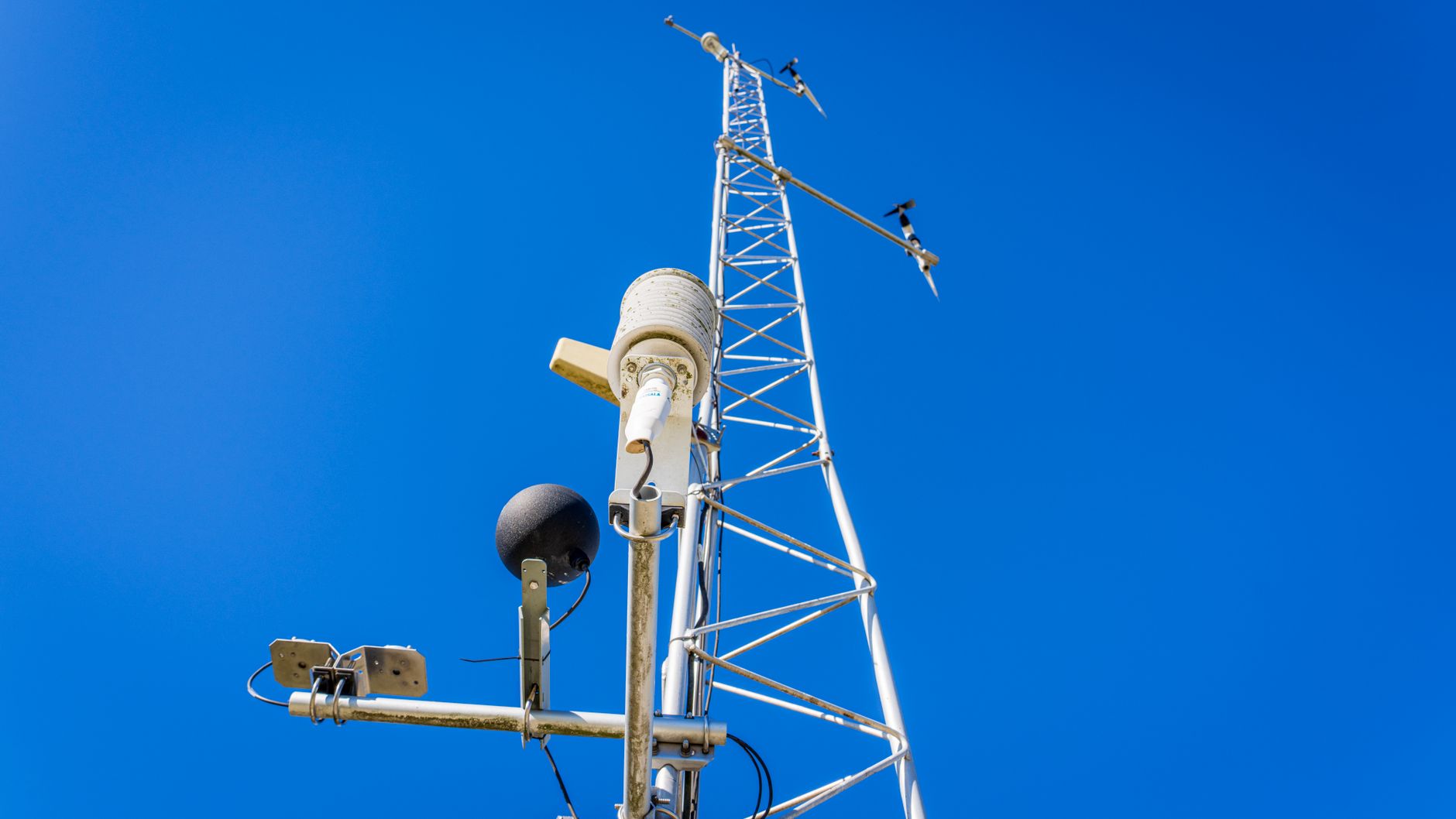 Close-up view of a communication tower with antennas under a clear blue sky, showcasing modern technology.