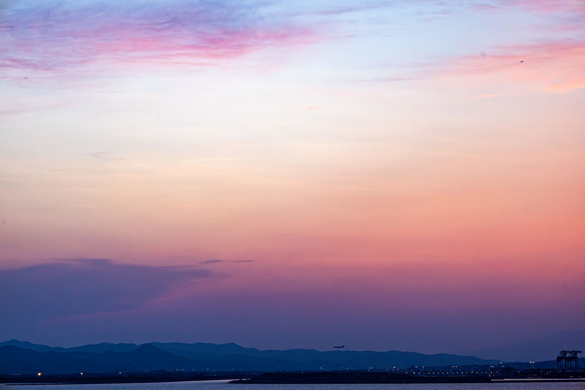 Tranquil twilight sky over a serene landscape with distant mountains, captured in vivid colors.