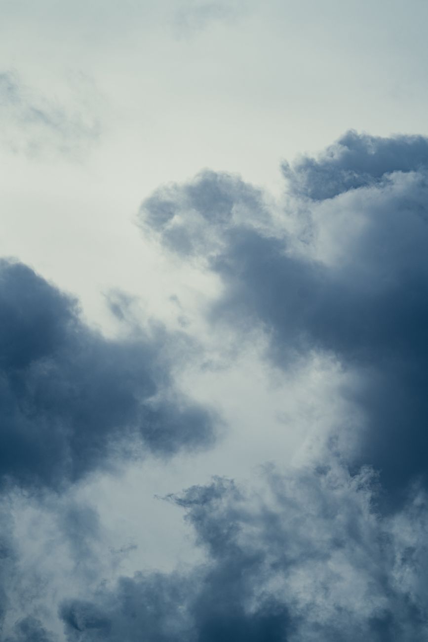 Moody cloudscape featuring dark, billowing clouds against a pale sky.