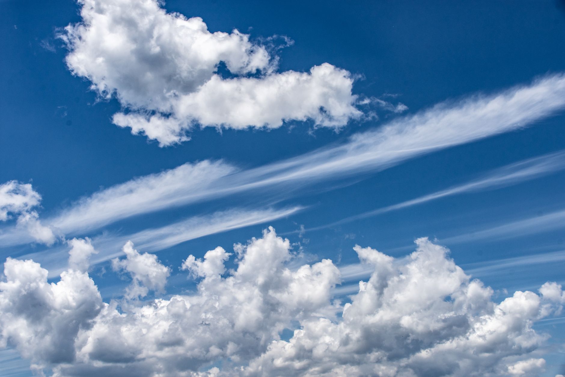 Vivid blue sky filled with fluffy cumulus and cirrus clouds on a sunny day.