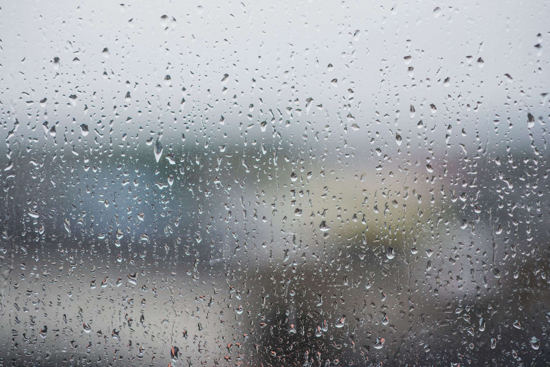 Close-up of raindrops on a window creating a moody and abstract view.
